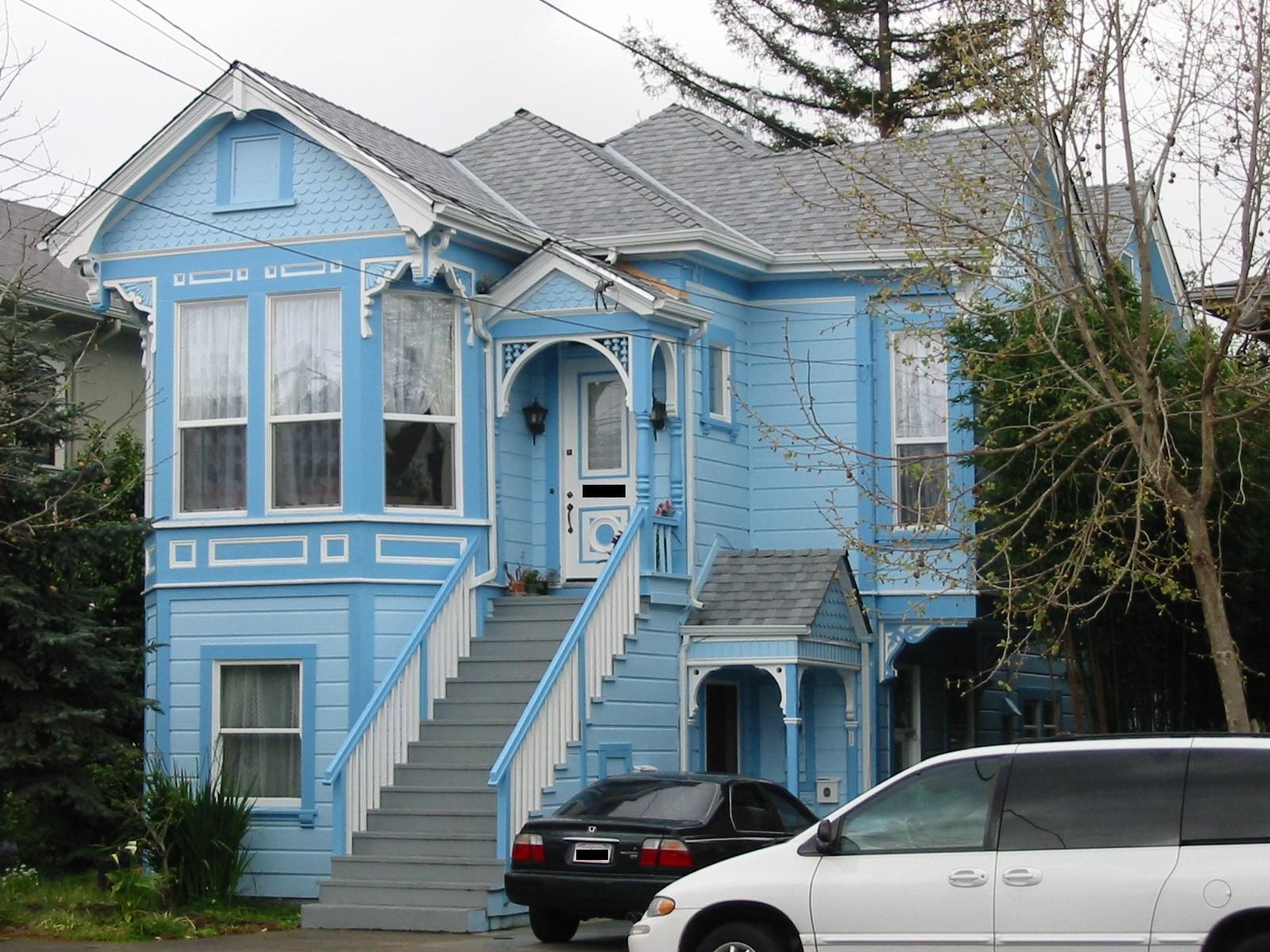 A pale blue Victorian house with bay windows and front stairs in Alameda