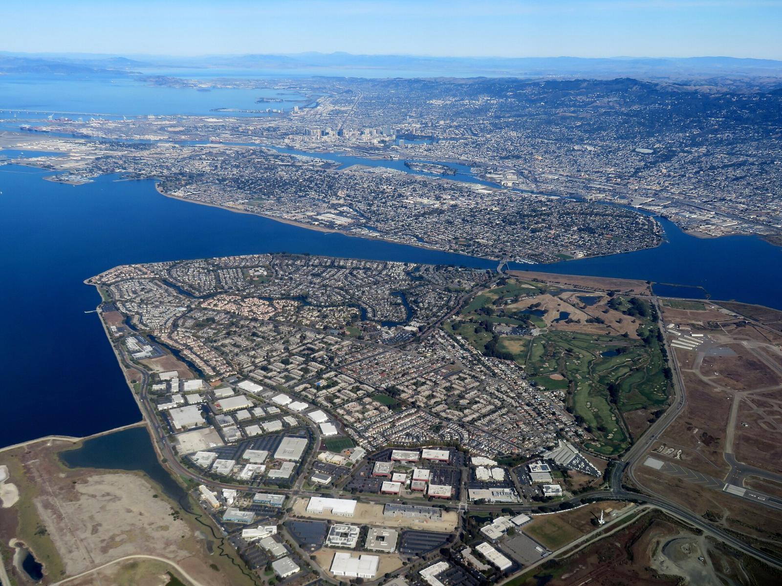 Aerial view of Bay Farm Island with its homes, lagoons and the bay