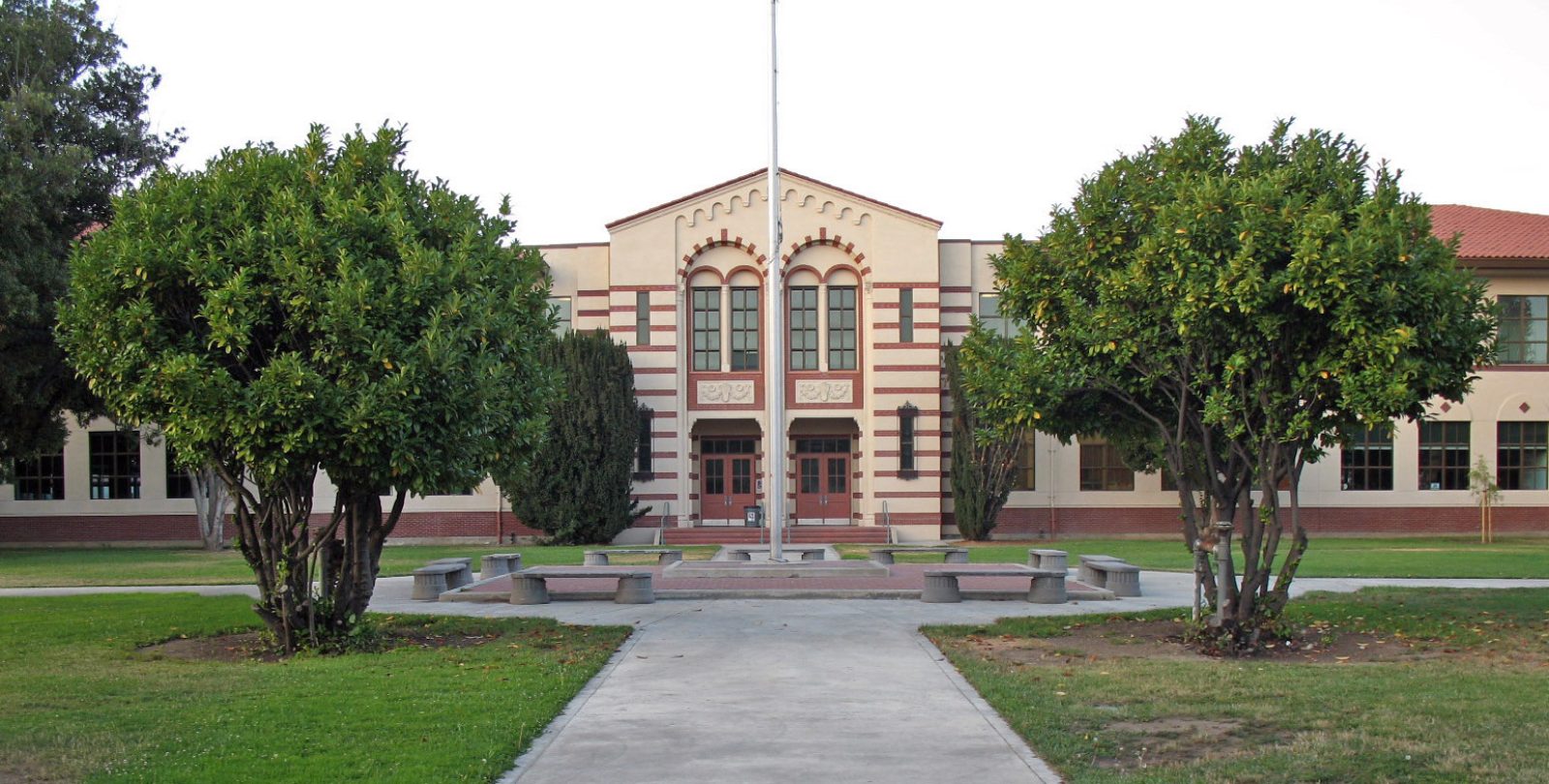 The historic main building of Washington High School behind a tree-lined lawn