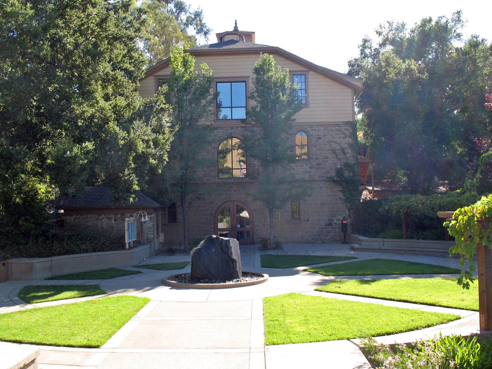 The historic DeMartini Winery building with a lawn and trees in Clayton