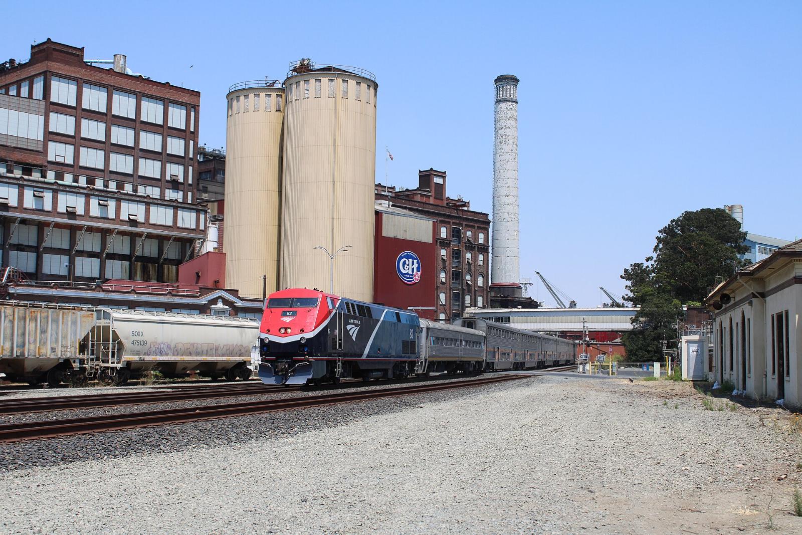 A passenger train passing the tall silos of the sugar refinery in Crockett