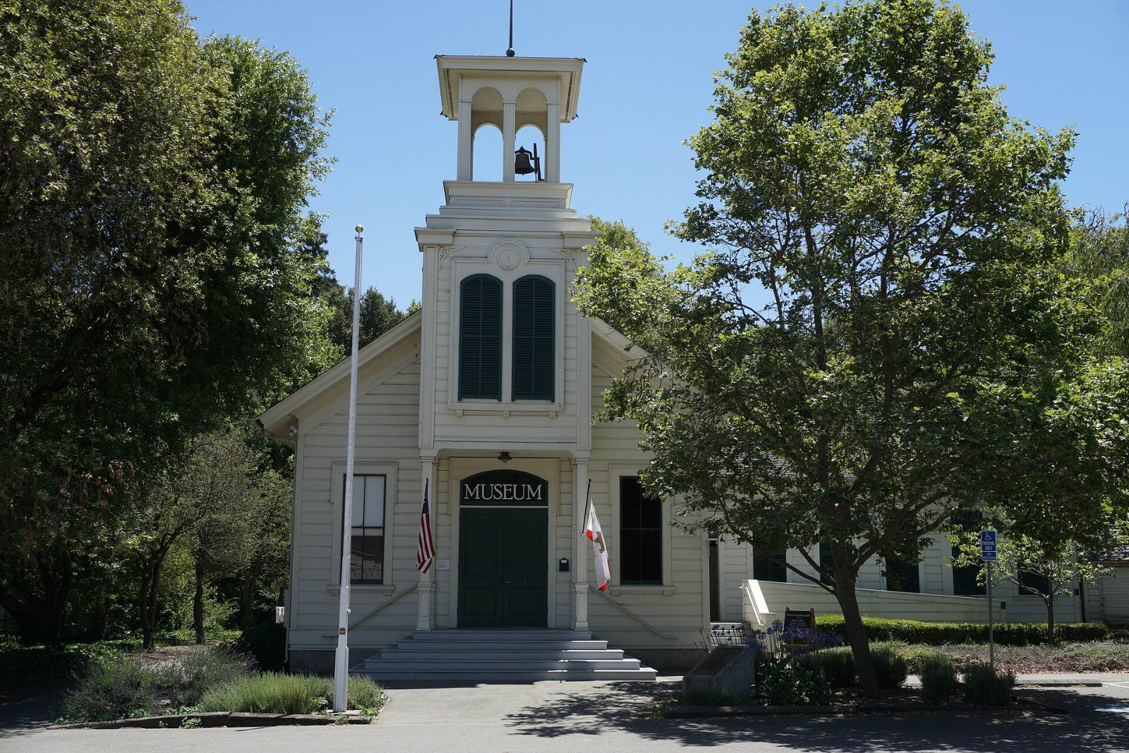 The white Murray Schoolhouse with its bell tower among trees