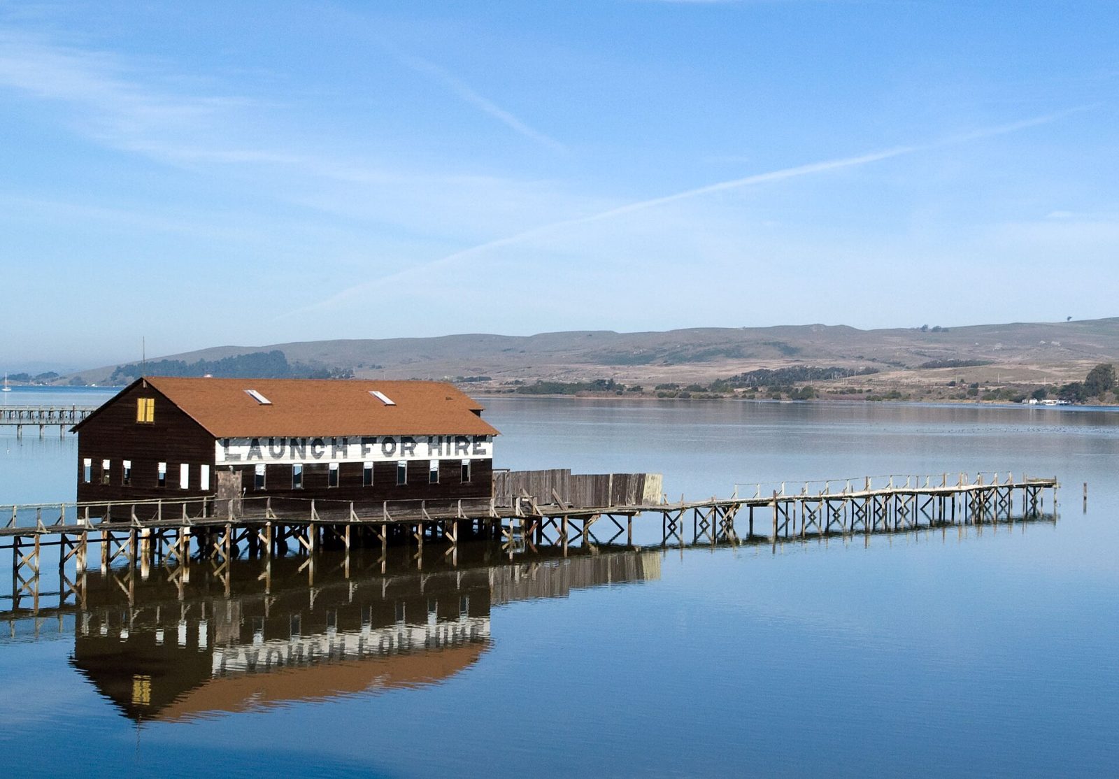 The red Brock Schreiber Boathouse on stilts over Tomales Bay in Inverness