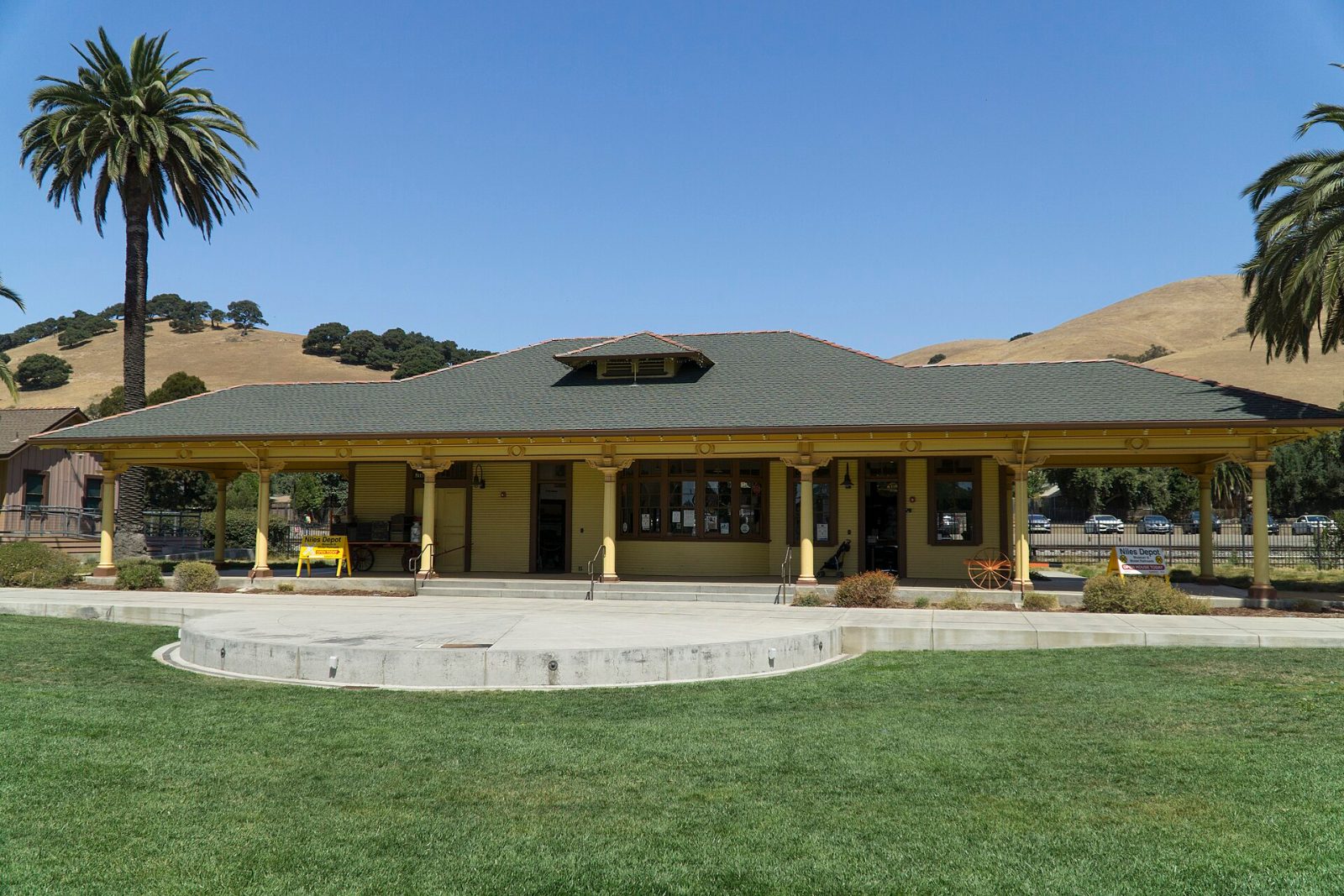 The restored Niles train depot with palm trees and green hills behind it