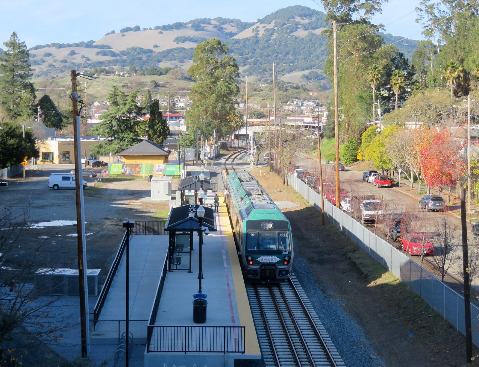 A SMART train at the Novato Downtown station with hills in the distance