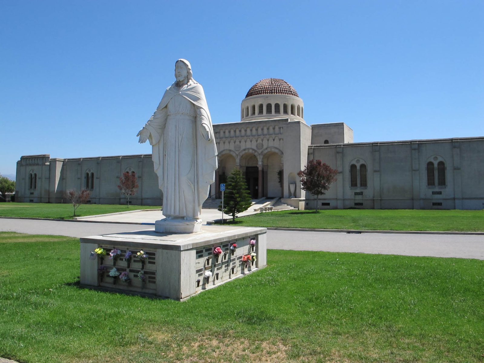 A white statue in front of the domed mausoleum at Oak Hill Memorial Park