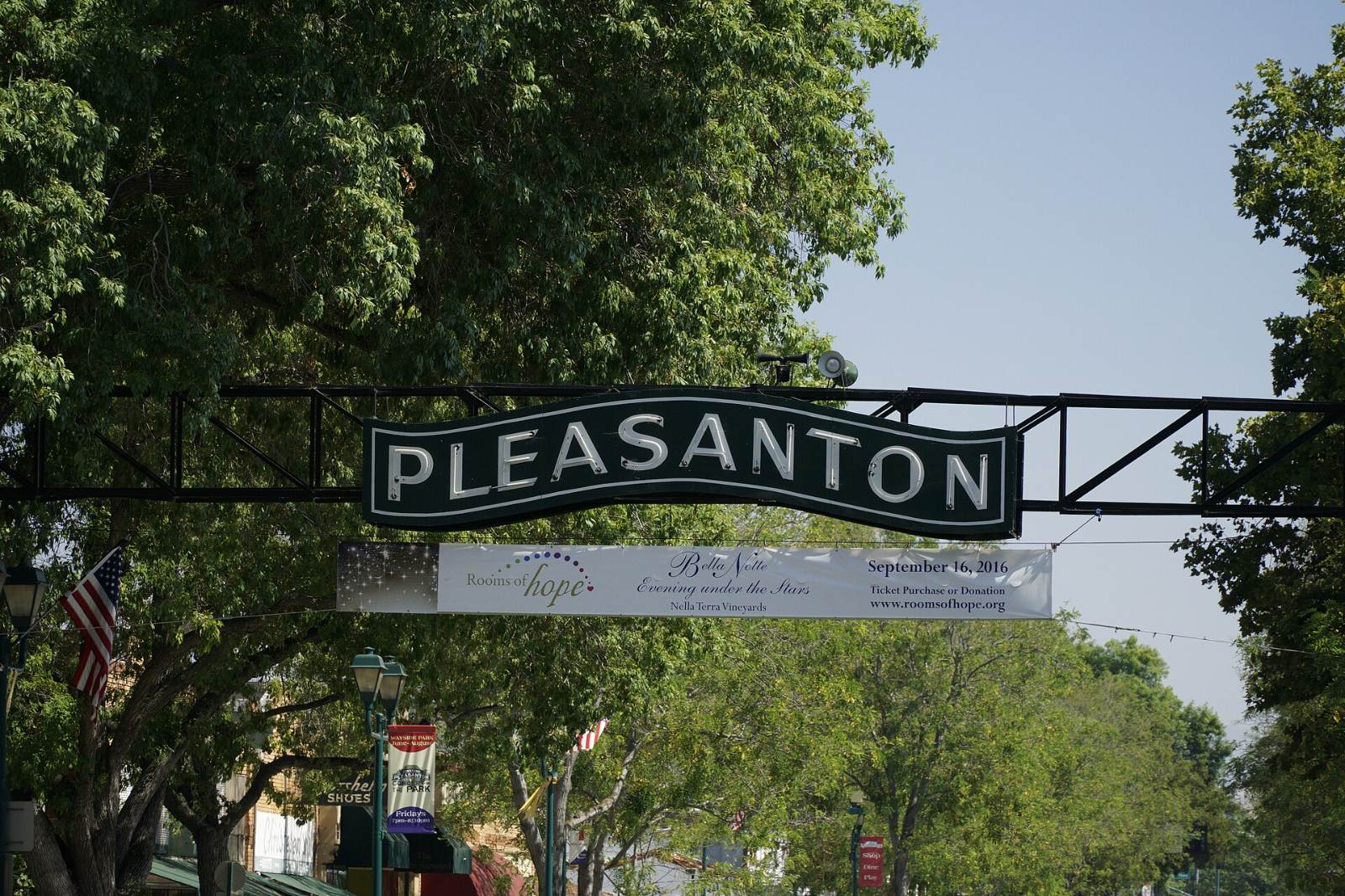 The arched Pleasanton sign over Main Street with trees on both sides