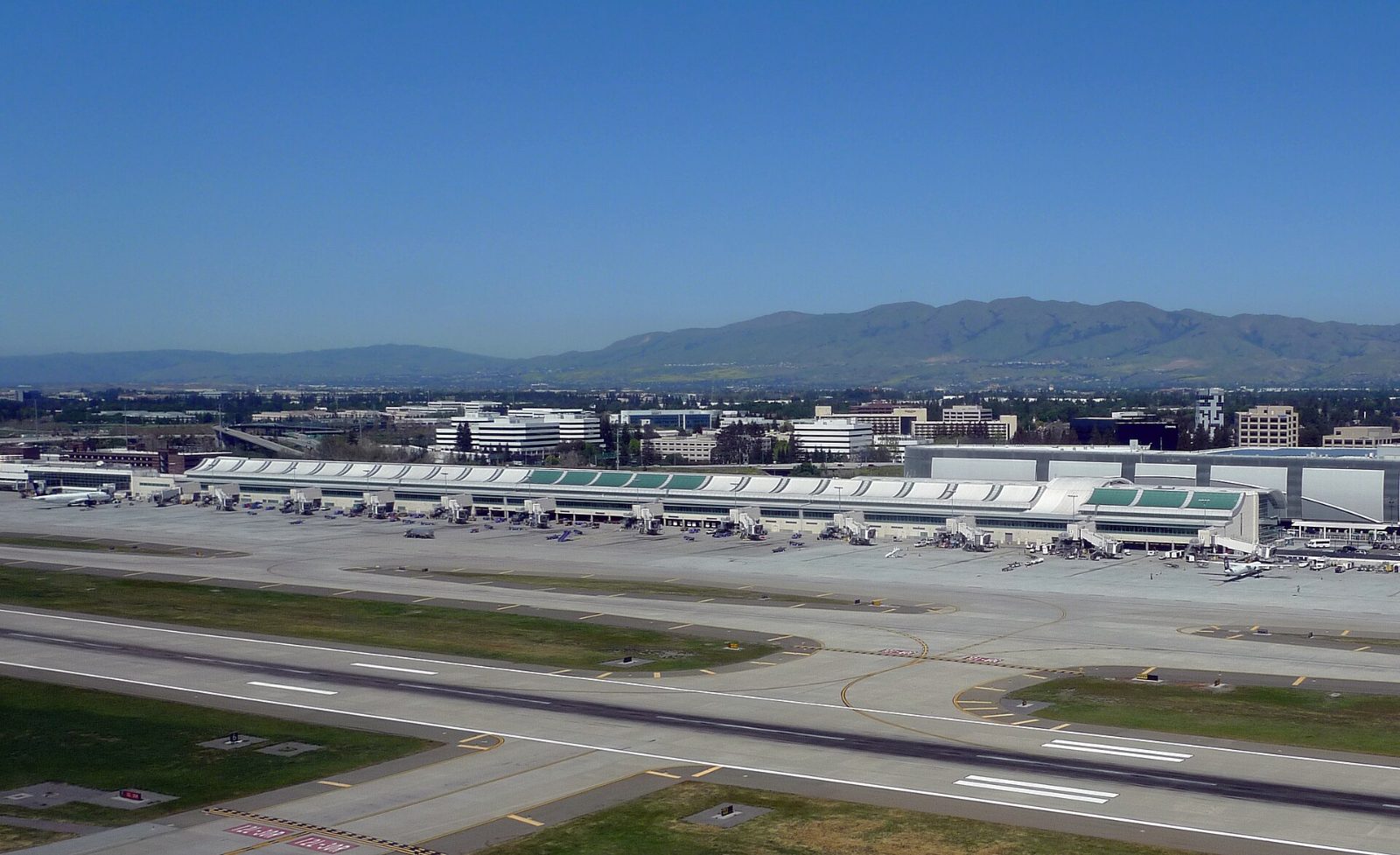 San José Mineta International Airport terminal and runway with hills beyond