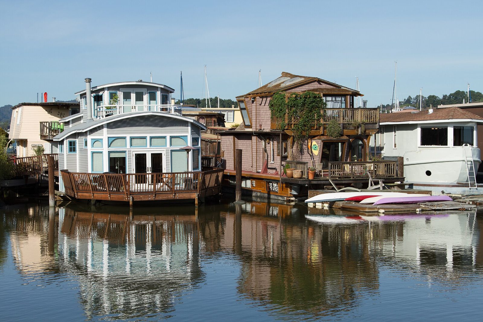 Colorful houseboats on a dock in Sausalito with hills behind them