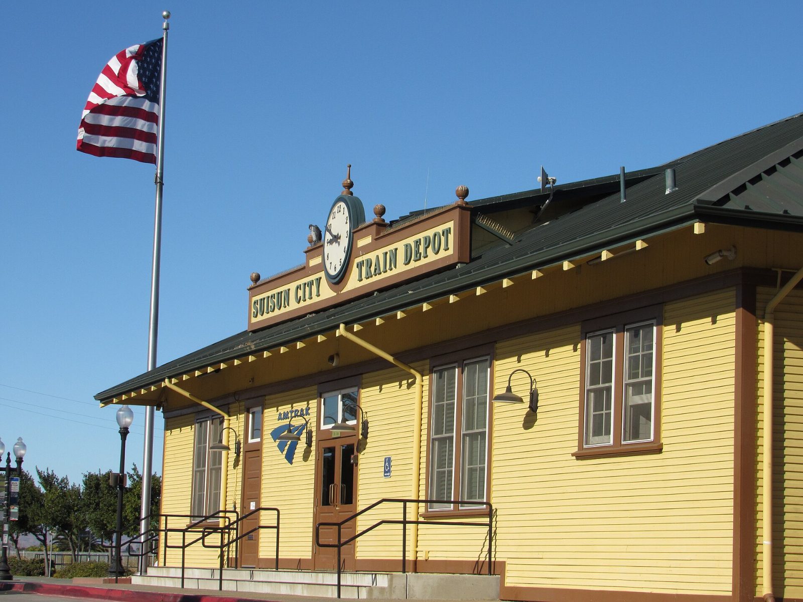 The historic yellow Suisun City train depot with an American flag in front